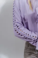 Camisa de cuero ovino desgastado color lila, con escote en V y cordones cruzados en el centro. Presenta mangas largas con recortes y cordones decorativos a lo largo de los brazos.