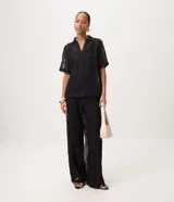 Pantalón de tricot negro con corte wide leg, transparencia delicada y bordado abstracto en relieve. Cuenta con cintura elástica y caída fluida.
