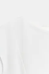 Top blanco de piqué con cuello redondo y mangas cortas, de corte entallado en la cintura y bajo redondeado con acabado en peplum.