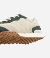 Championes de estilo jogging con diseño de paneles en tonos beige y verde oscuro. Presentan una combinación de malla técnica y refuerzos en material sintético, con suela dentada en color marrón y entresuela blanca.