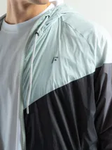 Campera deportiva negra de nylon impermeable con capucha y cierre frontal. Presenta puños y cintura elásticos de tejido acanalado. Tiene un pequeño logo blanco en el pecho.