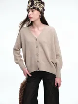 Cardigan de punto color beige con escote en V, cierre frontal con botones, hombros caídos y mangas largas con puños ajustados.