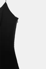 Vestido corto color negro confeccionado en tejido elástico, con escote redondo, tirantes finos y cierre lateral con cremallera oculta.