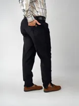 Pantalón de pana negro de corte recto, con bolsillos laterales y traseros. Se ajusta a la cintura con cinturón de cuero negro.