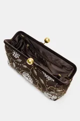 Bolso tipo clutch de efecto terciopelo color marrón, con bordados florales, apliques de brillos y lentejuelas. Cuenta con cierre de clip metálico dorado y cadena metálica extraíble.