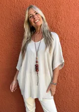 Blusa de corte holgado y diseño minimalista, confeccionada en tela texturizada color beige, con escote en V y mangas cortas tipo kimono.