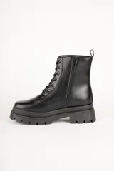 Borcegos negros de caña baja en símil cuero, con apliques de hebillas metálicas y cierre lateral. Plataforma de 5cm de alto.