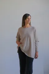 Sweater de punto con acabado brillante, color visón, de corte holgado y mangas largas con puños ajustados. Presenta un diseño con costuras verticales decorativas en el frente.