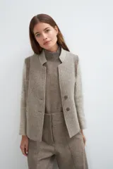 Chaqueta corta color marrón con cuello solapa y diseño con patchwork de telas. Manga larga con detalle de coderas aplicadas. Cierre frontal mediante botones y bolsillos ojal. Con forro.