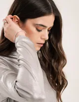 Polera dorada de cuello alto y manga larga, confeccionada en tejido elastizado con terminación metalizada.