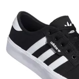 Championes Adidas modelo Seeley XT de estilo urbano, confeccionados en lona negra con las icónicas tres tiras laterales en blanco. Presentan suela de goma blanca vulcanizada y cierre de cordones.