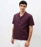 Camisa de manga corta con cuello solapa, cierre frontal de botones y diseño a rayas verticales. Confeccionada en algodón con textura.