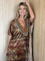 Vestido midi de terciopelo con estampado en tonos tierra y verdes. Presenta un corte holgado, mangas cortas y un escote en V destacado por un aplique artesanal de cuero en tonos verdes y marrones, unido con bordados a mano.