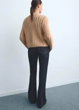 Pantalón de jean estilo flare con tiro alto, confeccionado en tejido de algodón con elasticidad. Presenta diseño de cinco bolsillos, cierre de botón y cremallera, y trabillas para cinturón.