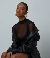Body de manga larga confeccionado en tul negro con transparencias, presenta cuello alto y un ajuste ceñido al cuerpo.