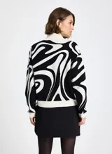 Sweater de punto con diseño estampado abstracto en blanco y negro, cuello alto, mangas largas y puños acanalados.
