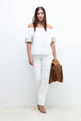 Blusa blanca con escote bardot y mangas cortas abullonadas con bordados dorados.