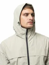 Campera rompevientos de nylon color gris, con capucha ajustable, cierre frontal completo, bolsillos laterales con cierre, puños elásticos y ruedo ajustable.