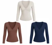 Remera blanca de manga larga con escote en V profundo, decorada con detalles de encaje en el borde del escote y costuras frontales. Presenta un ajuste entallado al cuerpo.