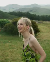 Vestido corto con estampado floral en tonos verdes y negros, escote en V y tirantes finos.