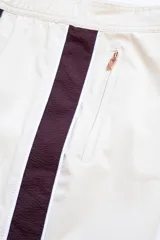 Short de baño color crema con tira lateral color borgoña y cordón de ajuste en la cintura.