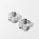 Aros plateados con forma de flor con textura martillada y centro abultado.