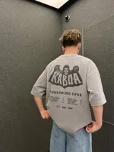Remera oversize gris con efecto acid wash y estampa frontal con la leyenda "WORLDWIDE TOUR" en tipografía gótica.