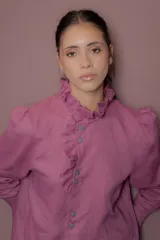 Blusa de lino color fucsia con cuello alto y volados frontales. Presenta mangas largas abullonadas y cierre frontal con botones a tono.