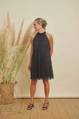 Vestido corto negro con escote halter adornado con perlas, diseño holgado y detalles de perlas en la parte inferior de la falda.