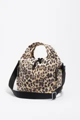 Bolso bandolera de estructura blanda marca Bimba y Lola, confeccionado en nylon con estampado animal print de leopardo. Presenta doble asa de mano integrada, correa de tejido negra regulable y extraíble, bolsillos laterales con cierre y logo metálico de la marca en el frente.