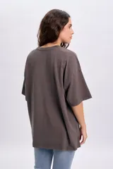 Remera oversize gris claro de manga corta, con estampa frontal inspirada en el rock con inscripciones y alas.