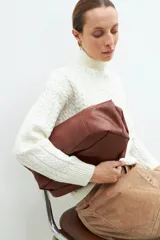 Polera color crudo con cuello alto y tejido con diseño de trenzas.