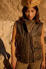 Chaleco de cuero con efecto desgastado, diseño utilitario con cuello alto y cuatro bolsillos cargo frontales con detalles de estribos metálicos.