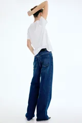 Pantalón jean de denim azul, tiro alto, con diseño wide leg de cinco bolsillos y cierre frontal con botón y cremallera.