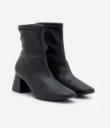 Bota de caña corta color negro, confeccionada en material sintético, con taco mediano bloque y puntera cuadrada.