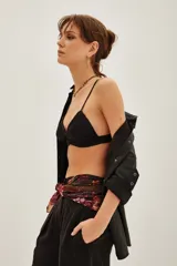 Crop top tipo bralette de encaje negro con detalles bordados y terminaciones delicadas. Presenta breteles finos y un diseño triangular que se ajusta al cuerpo.