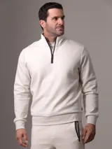 Buzo color crema de Calvin Klein confeccionado en mezcla de algodón y poliéster. Presenta cuello alto con media cremallera negra, puños y dobladillo con punto canalé.