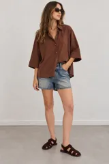 Camisa de lino blanca oversize, con cuello solapa, mangas anchas y cierre frontal con botones.