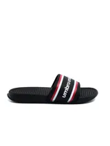 Chancletas Umbro color negro con plantilla texturizada, banda ancha superior con el nombre de la marca y franjas decorativas en rojo y blanco.