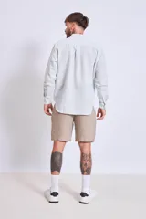 Camisa de corte regular con diseño de rayas verticales finas en tonos claros, cuello clásico y mangas largas con puños abotonados.