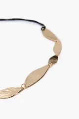 Cinturón dorado con piezas metálicas en forma de hoja martillada, unidas por una cuerda negra ajustable.