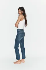 Jeans de tiro alto con diseño cropped flare, confeccionados en denim azul con acabado desgastado. Presentan cinco bolsillos, cierre frontal con cremallera y botón metálico, y bajo con terminación sin costuras.