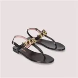 Sandalias negras de cuero con tira al tobillo y detalle de cadena dorada gruesa.