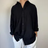 Camisa de lino de corte oversize, con cuello clásico, cierre frontal de botones y mangas largas con puños simples.