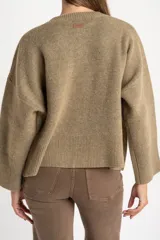 Sweater de lana de corte oversize, con cuello redondo y mangas largas con puños acanalados. Diseño de tejido liso en tono neutro.