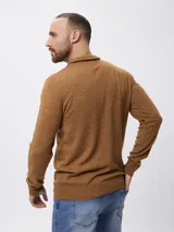 Sweater de tejido de punto en color azul, con cuello alto y cierre frontal parcial. Presenta mangas largas con puños acanalados y un pequeño detalle bordado en el pecho.