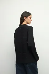 Polera marrón de tejido tramado, cuello alto y mangas largas acampanadas.
