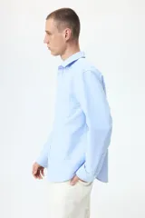 Camisa de algodón Oxford con cuello americano, bolsillo frontal y mangas largas con puños abotonados. Presenta un corte estándar y bajo redondeado.