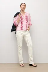 Blusa de manga tres cuartos con diseño a rayas verticales en color rosa y blanco. Presenta un escote en V con botones frontales y bordados florales en color rojo a lo largo de la parte delantera y en las mangas.