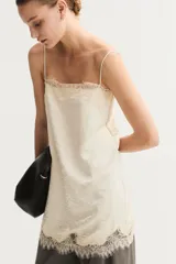 Vestido corto de satén color beige con breteles spaghetti ajustables, escote recto y detalles de encaje en el escote y el bajo.